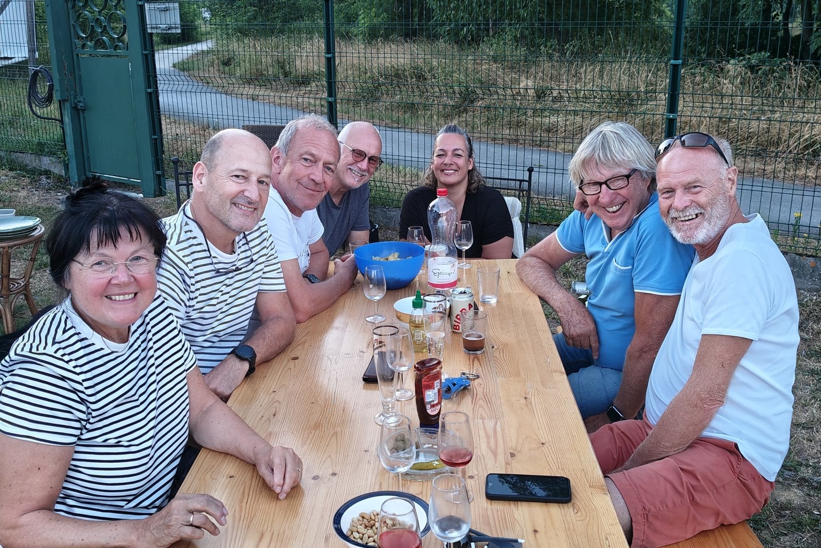 Sept membres du Nautic Club Kembs réunis autour d’une grande table en bois au bord du port, un soir d’été